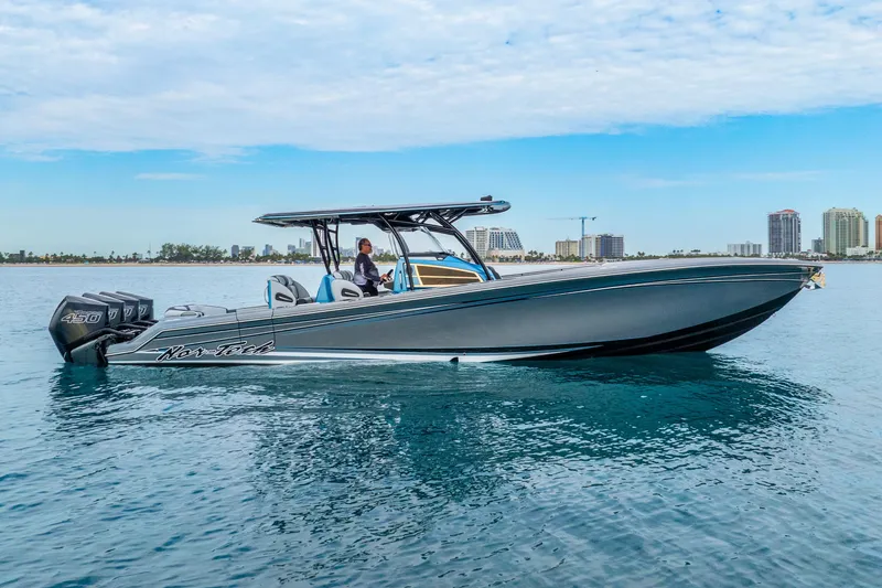 Slide: The Image of 2024 Nor-Tech 390 Sport Center Console boat on calm water, city skyline in background. - 2