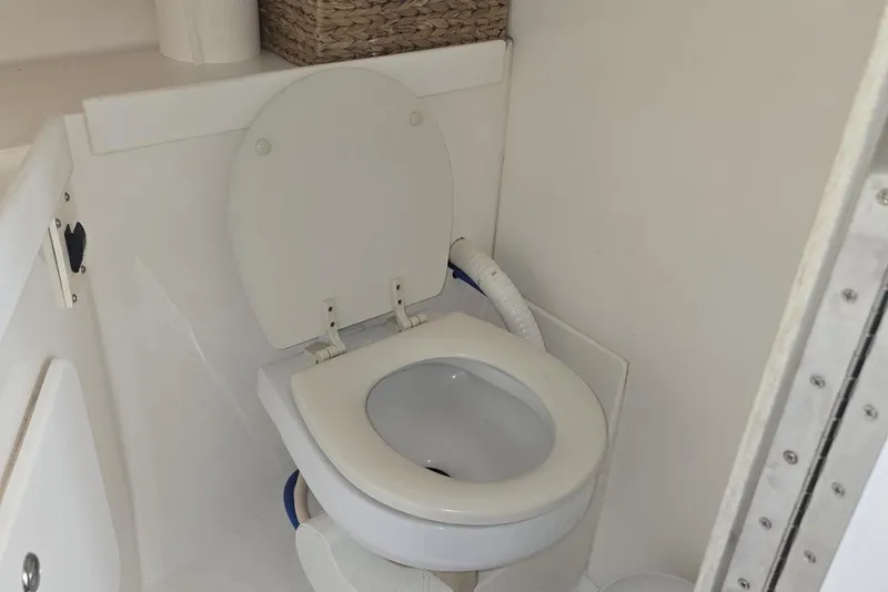 Slide: The Image of 2004 Stamas 290 Express boat bathroom with white marine toilet and storage basket. - 18