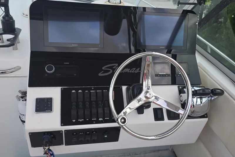 Slide: The Image of Control panel of a 2004 Stamas 290 Express boat with dual screens and steering wheel. - 20