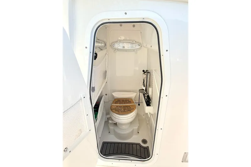 Slide: The Image of 2023 Sea Hunt Ultra 255 SE boat interior bathroom with toilet and storage. - 18
