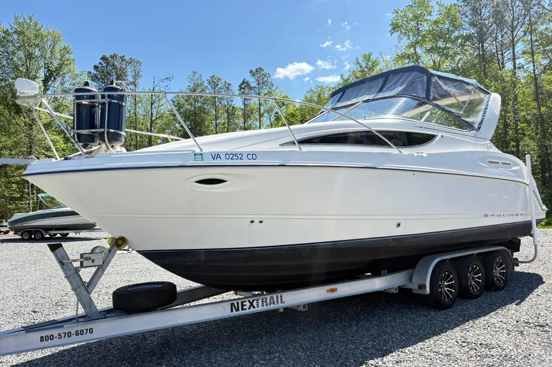 The Image of 2003 Bayliner 285 Ciera boat on trailer, parked outdoors with trees in background. - 1
