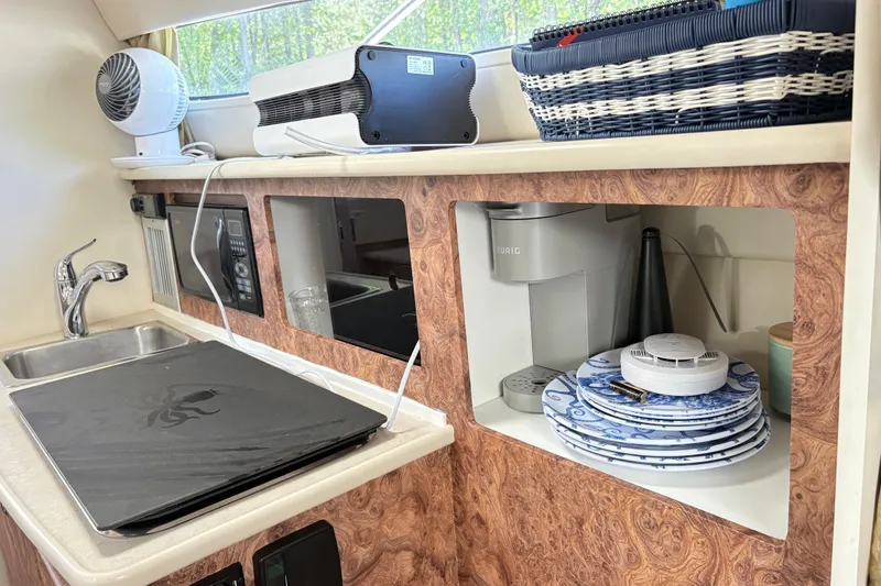 Slide: The Image of 2003 Bayliner 285 Ciera kitchen area with sink, appliances, and neatly stacked plates. - 16