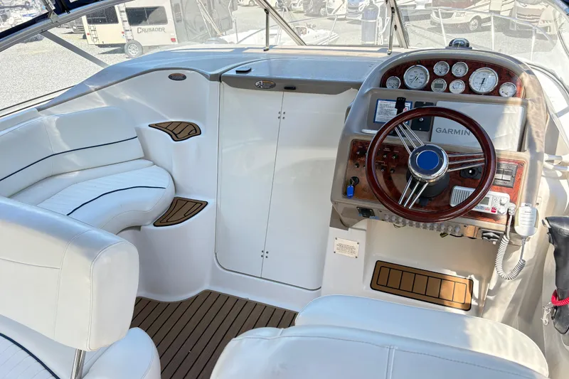 Slide: The Image of 2003 Bayliner 285 Ciera cockpit with white seating, wood accents, and Garmin navigation system. - 7