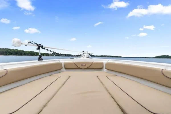 Slide: The Image of 2018 Sea Hunt Gamefish 27 boat with cushioned seating, on a calm lake under blue skies. - 11