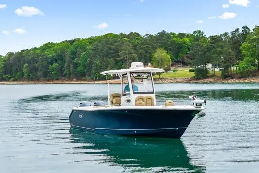 Slide: The Image of 2018 Sea Hunt Gamefish 27 boat on a calm lake with forested shoreline. - 2