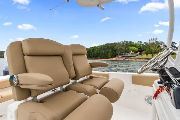 Slide: The Image of 2018 Sea Hunt Gamefish 27 boat interior with tan seating, steering wheel, and scenic water view. - 37