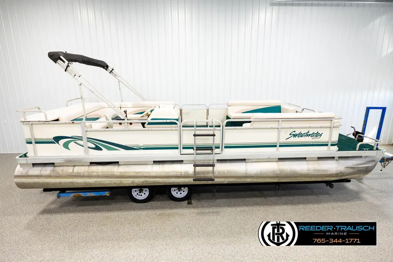The Image of 1998 Godfrey SW2423 pontoon boat with green accents in a showroom. - 1