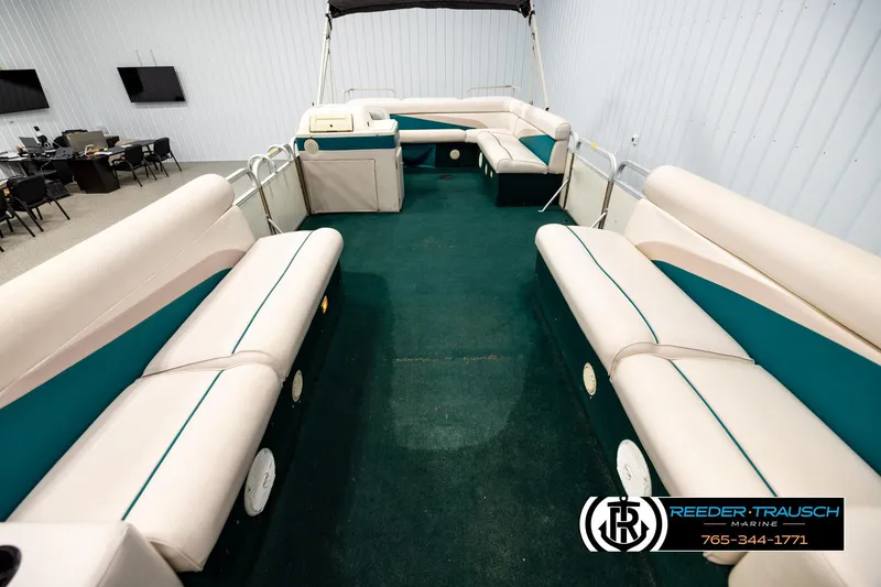 Slide: The Image of 1998 Godfrey SW2423 pontoon boat interior with green carpet and beige seating. - 13