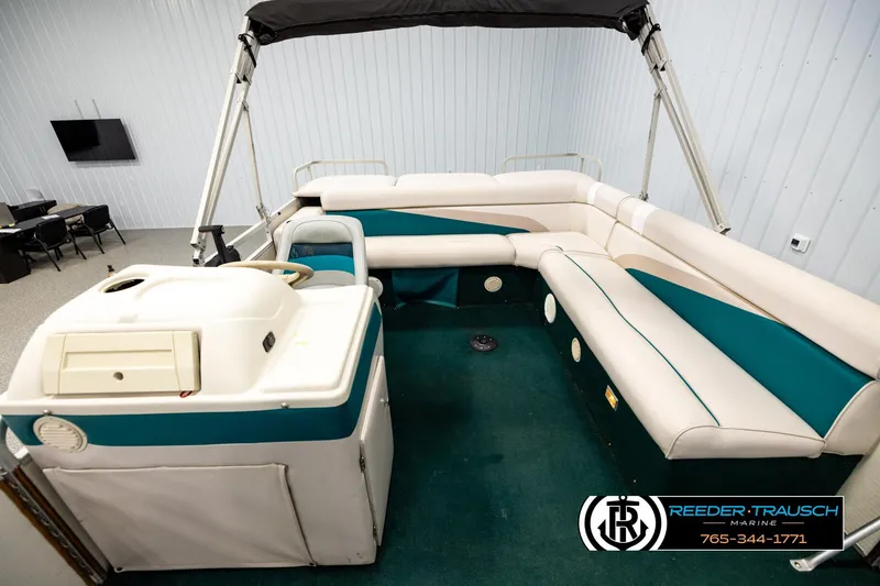 Slide: The Image of 1998 Godfrey SW2423 pontoon boat interior with teal and white seating, displayed indoors. - 14