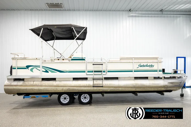 Slide: The Image of 1998 Godfrey SW2423 pontoon boat with canopy, displayed indoors on a trailer. - 5