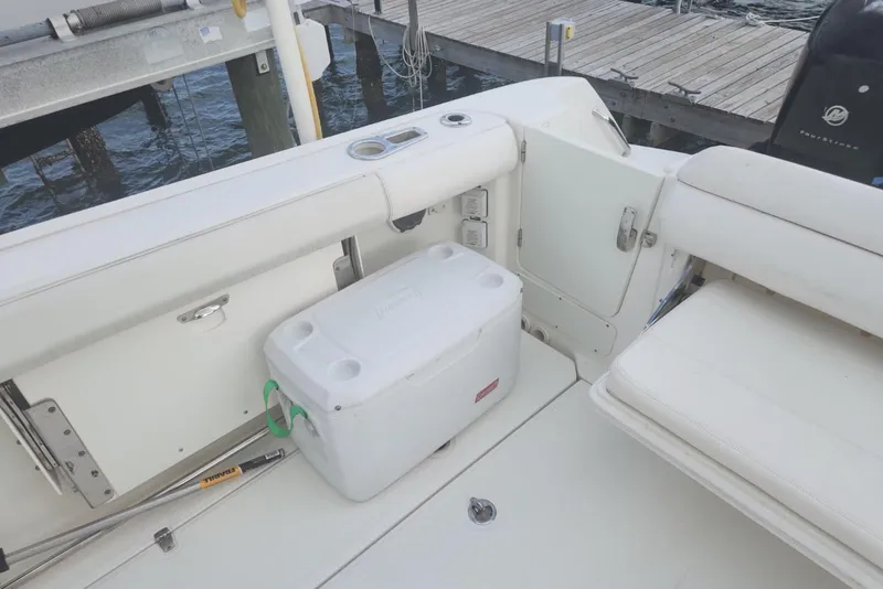 Slide: The Image of 2014 Boston Whaler 350 Outrage boat interior with cooler and seating near dock. - 12