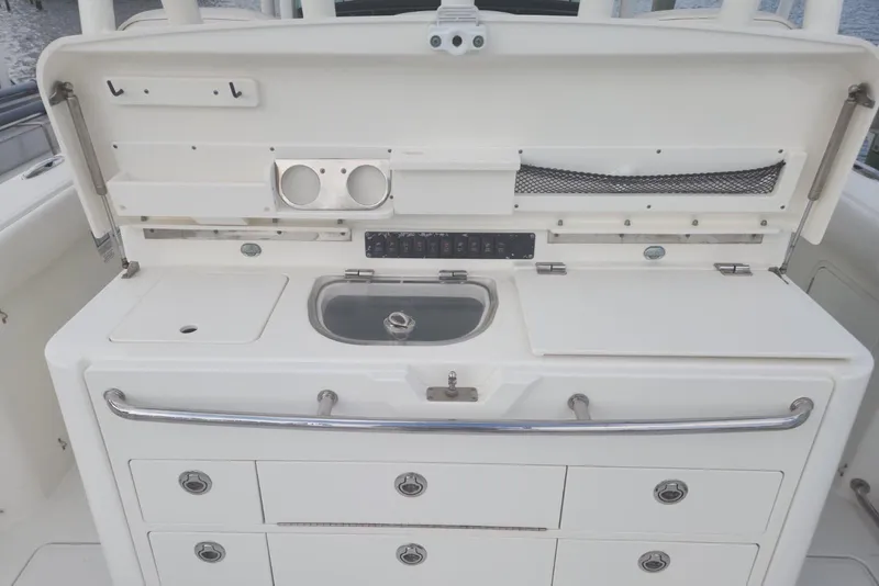 Slide: The Image of 2014 Boston Whaler 350 Outrage boat interior with storage compartments and sink. - 14