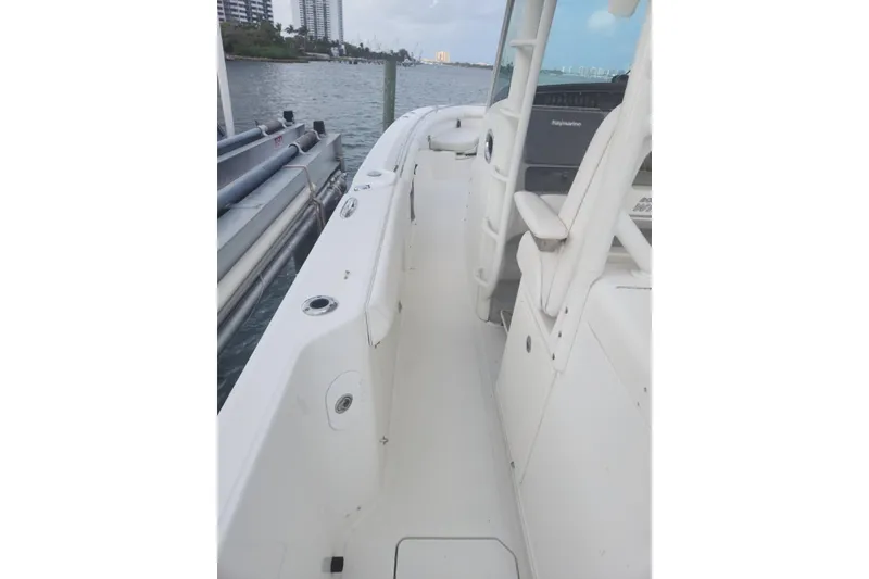 Slide: The Image of 2014 Boston Whaler 350 Outrage boat docked, showcasing sleek white deck and seating. - 18