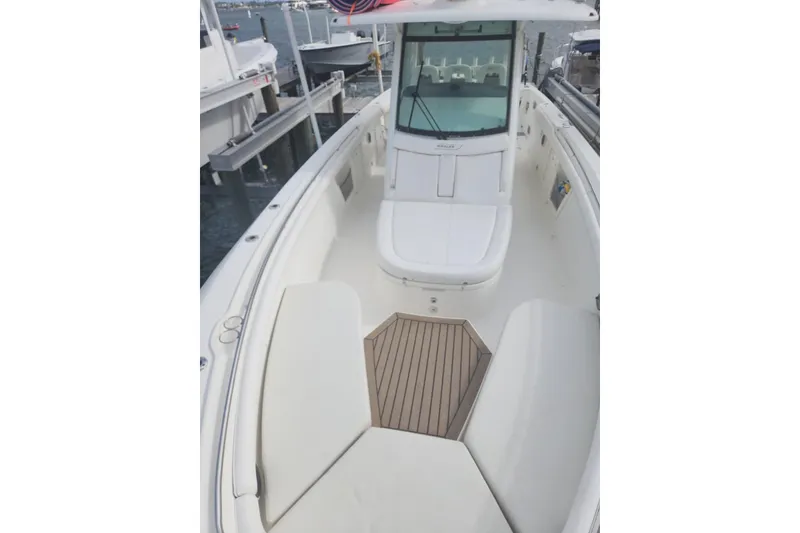 Slide: The Image of 2014 Boston Whaler 350 Outrage boat interior with cushioned seating and wooden flooring. - 23