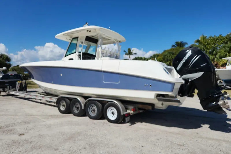 Slide: The Image of 2014 Boston Whaler 350 Outrage boat on trailer with Mercury engines, parked outdoors. - 3