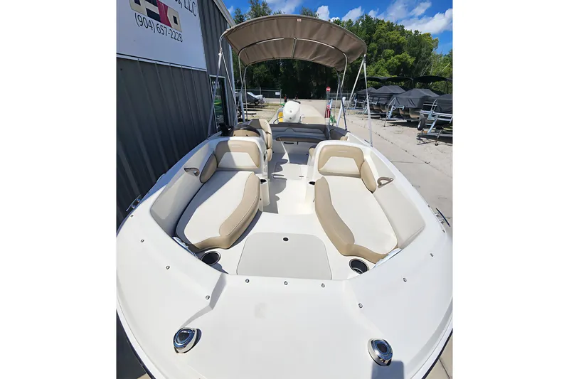 Slide: The Image of 2019 Stingray 182 SC boat with beige seating and canopy, parked outdoors. - 4