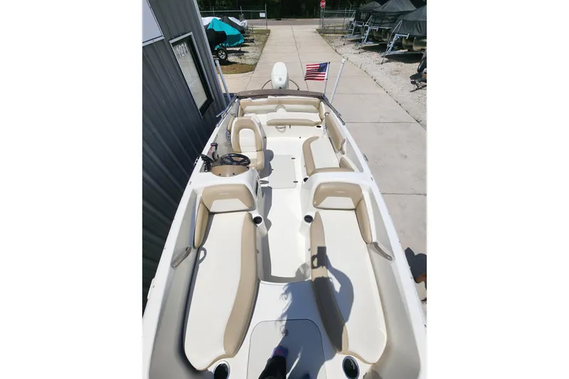 Slide: The Image of 2019 Stingray 182 SC boat with beige seating and American flag on dock. - 5