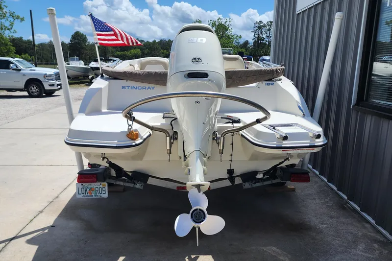 Slide: The Image of 2019 Stingray 182 SC boat with outboard motor, parked near a building. - 6