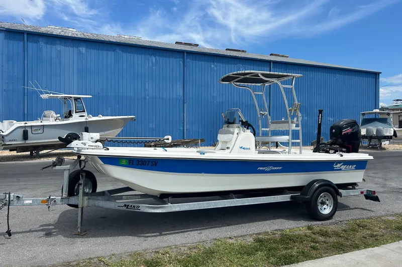 The Image of 2021 Mako Pro Skiff 19 CC boat on trailer, parked near blue building. - 1