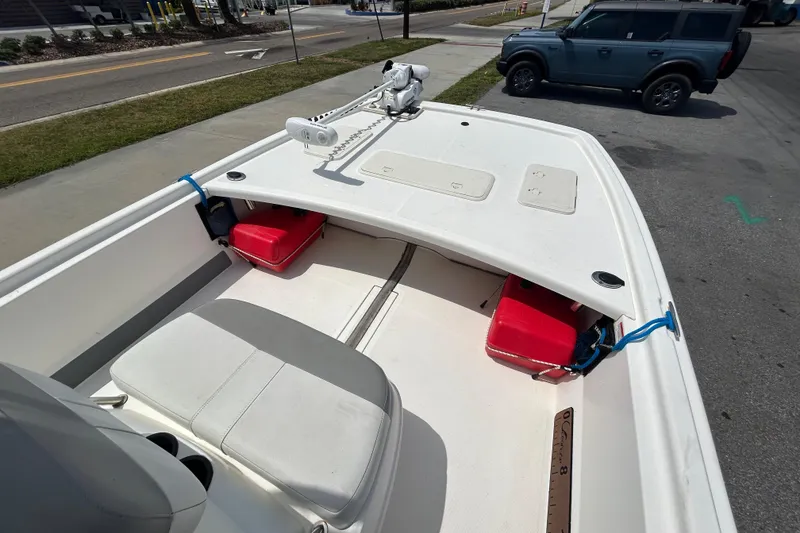 Slide: The Image of 2021 Mako Pro Skiff 19 CC boat with seating and storage, parked near a road. - 14