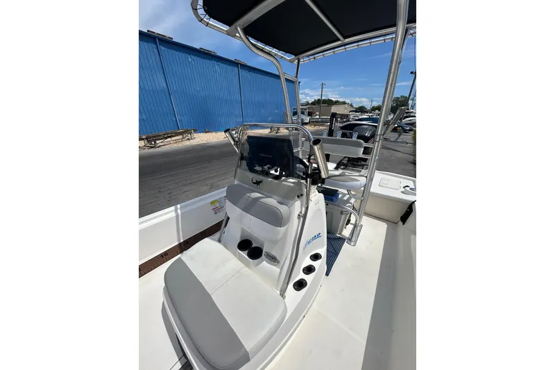 Slide: The Image of 2021 Mako Pro Skiff 19 CC boat interior with console and seating, docked outdoors. - 17