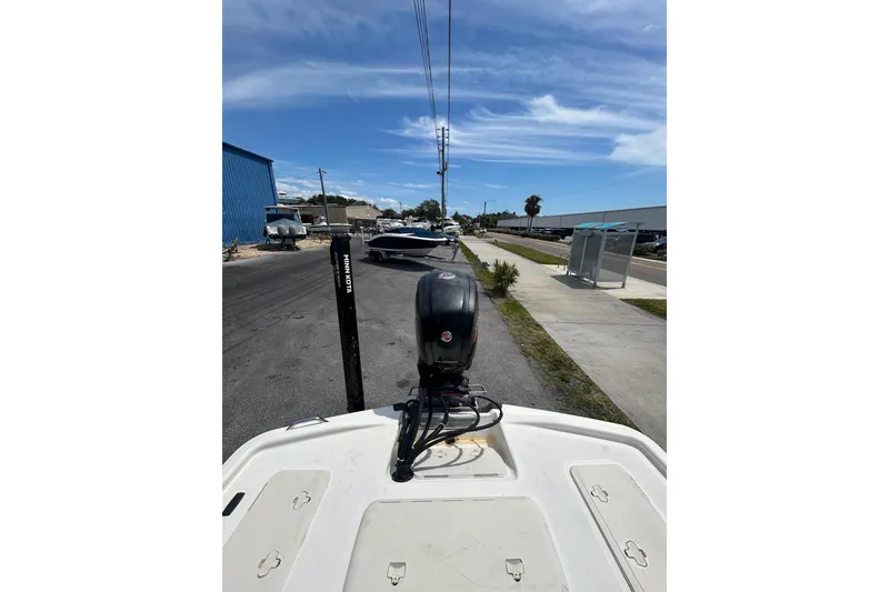 Slide: The Image of 2021 Mako Pro Skiff 19 CC boat with Minn Kota motor on a sunny street. - 19