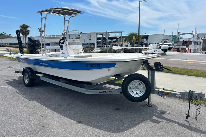 Slide: The Image of 2021 Mako Pro Skiff 19 CC boat on trailer, parked near marina. - 6