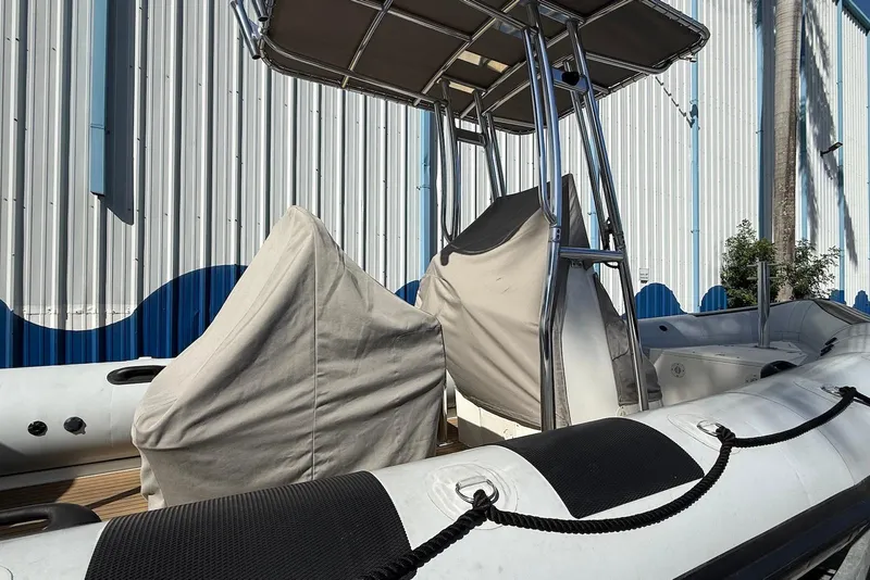 Slide: The Image of 2018 Ribcraft 7.8 boat with covered seats, docked near a corrugated metal wall. - 16