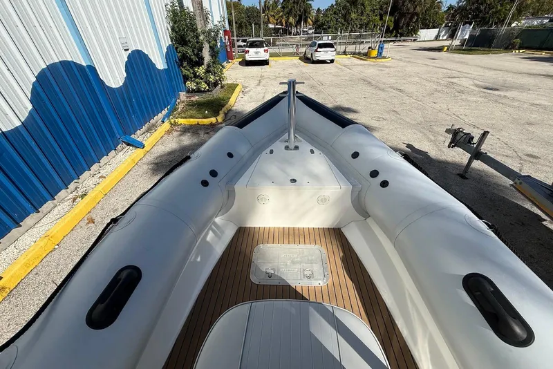 Slide: The Image of 2018 Ribcraft 7.8 inflatable boat with wooden deck, parked outdoors near a blue building. - 9