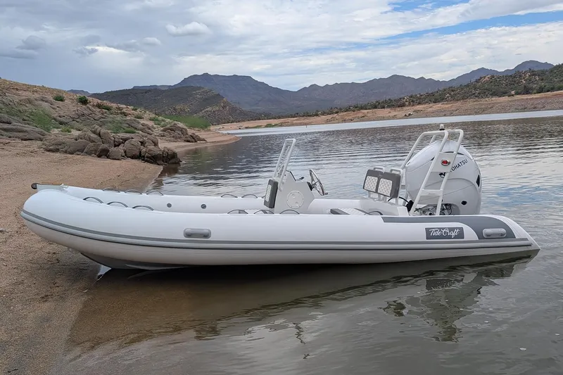 Slide: The Image of Manufacturer Provided Image: 2025 Tide Craft Kodiak 16 inflatable boat on a serene lake shore. - 1
