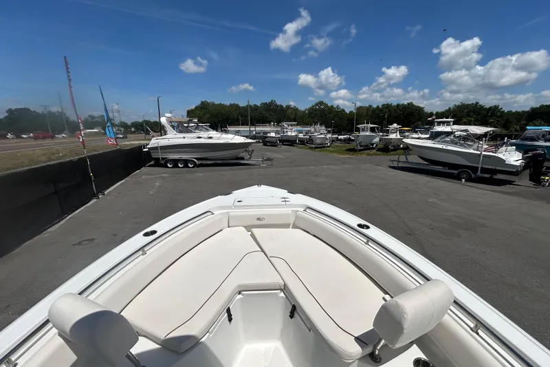 Slide: The Image of 2021 Sea Hunt Ultra 234 boat displayed in a sunny outdoor showroom. - 22
