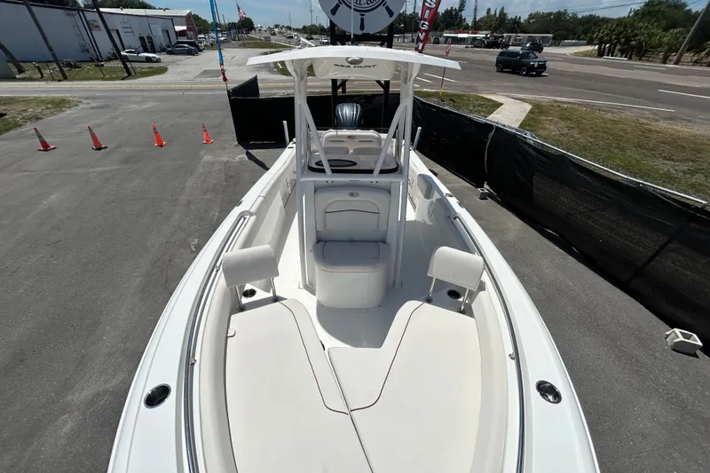 Slide: The Image of 2021 Sea Hunt Ultra 234 boat with spacious deck and seating, parked on a paved lot. - 27