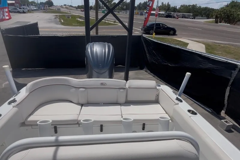 Slide: The Image of 2021 Sea Hunt Ultra 234 boat interior with seating and motor, parked near a road. - 37
