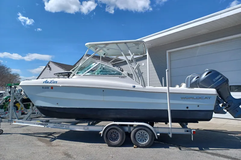 Slide: The Image of 2020 World Cat 230 DC boat on trailer, parked outside a garage under a clear blue sky. - 20