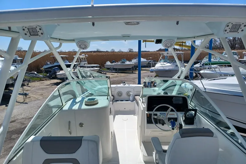 Slide: The Image of 2020 World Cat 230 DC boat interior with steering wheel and seating, docked among other boats. - 24