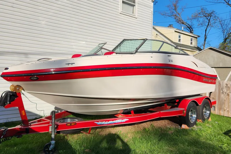 The Image of 2012 Rinker 216 Captiva Bowrider on red trailer, parked beside a house. - 0