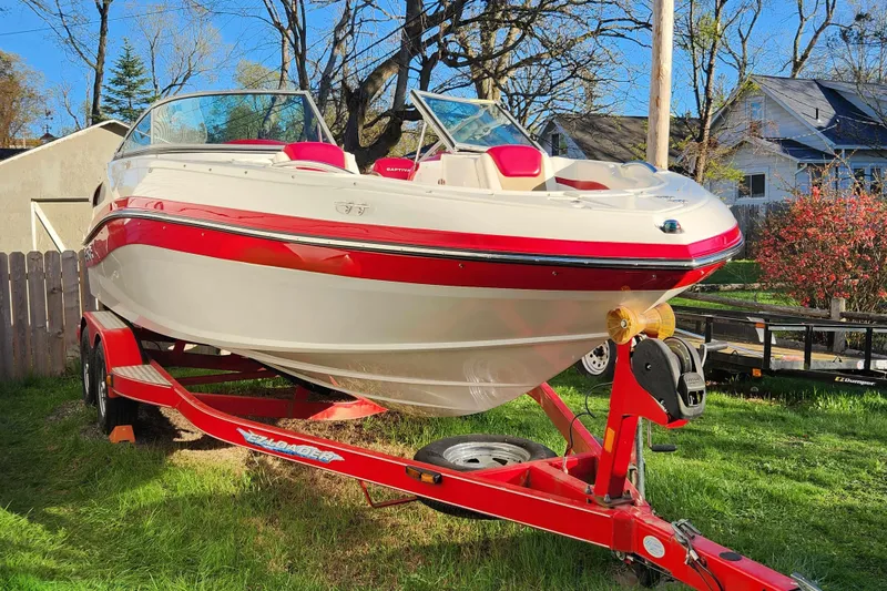 Slide: The Image of 2012 Rinker 216 Captiva Bowrider on red trailer, parked on grass. - 7