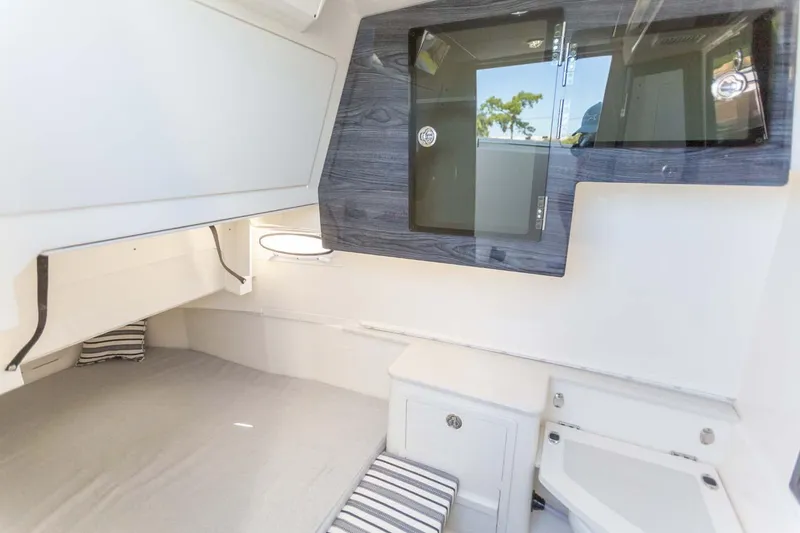Slide: The Image of Manufacturer Provided Image: 2024 Cobia 350 Center Console cabin interior with bed, storage, and window. - 20