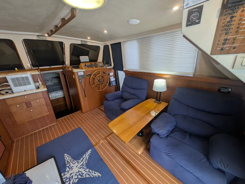 Slide: The Image of Interior of a 2001 Mainship 390 Trawler with wood flooring and blue recliners. - 43