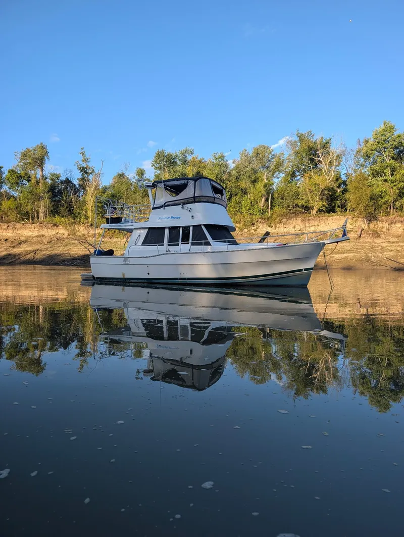 Slide: The Image of 2001 Mainship 390 Trawler on calm water near wooded shoreline. - 7