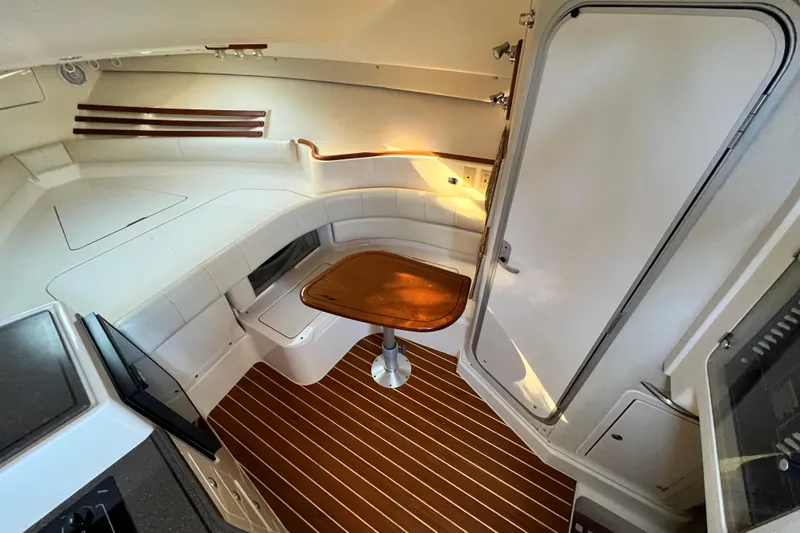 Slide: The Image of 2004 Grady-White Express 330 cabin interior with seating and wooden table. - 19