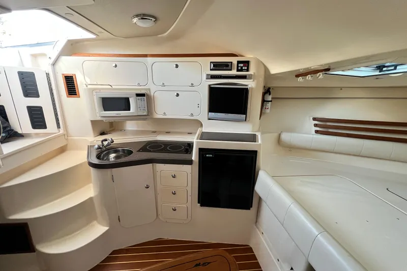 Slide: The Image of 2004 Grady-White Express 330 cabin interior with kitchenette and seating area. - 21