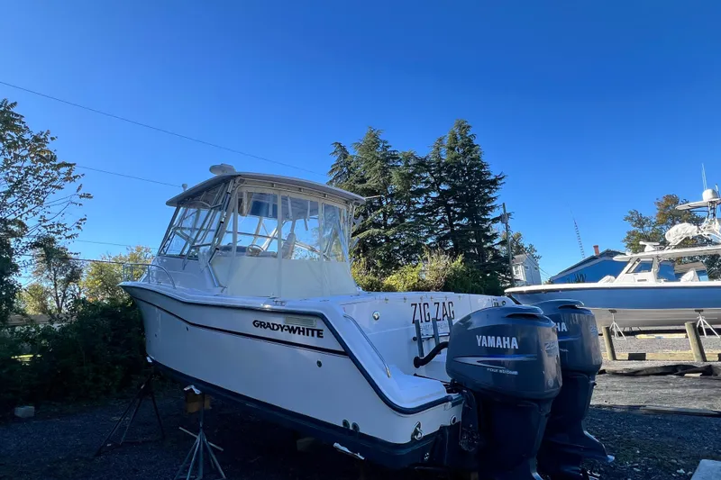 Slide: The Image of 2004 Grady-White Express 330 boat with Yamaha engines, parked outdoors under clear blue sky. - 5