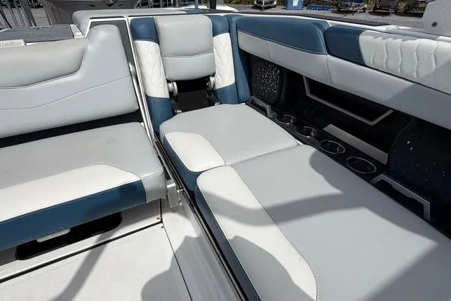 Slide: The Image of 2021 Malibu M240 boat interior with white and blue seating, cup holders, and quilted accents. - 13