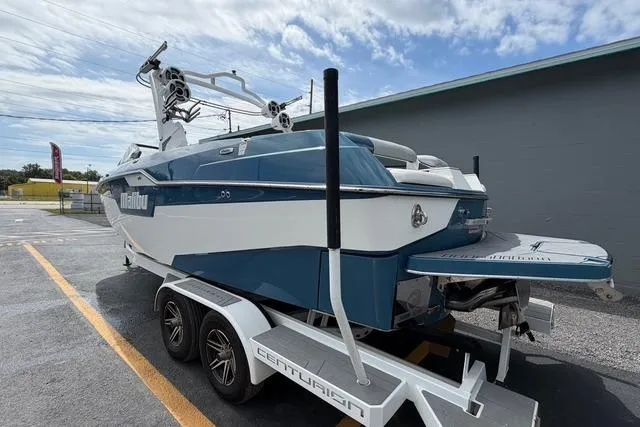 Slide: The Image of 2021 Malibu M240 boat on trailer, blue and white design, parked outdoors. - 3