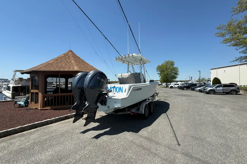 Slide: The Image of 2024 Contender 25 Tournament boat on trailer, parked near a gazebo under clear blue sky. - 2