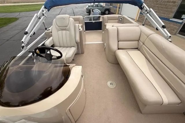 Slide: The Image of 2012 Bennington 2574 GCW pontoon boat interior with beige seating and steering console. - 13