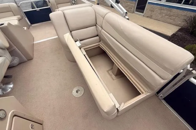 Slide: The Image of 2012 Bennington 2574 GCW boat interior with beige seating and storage compartment. - 14