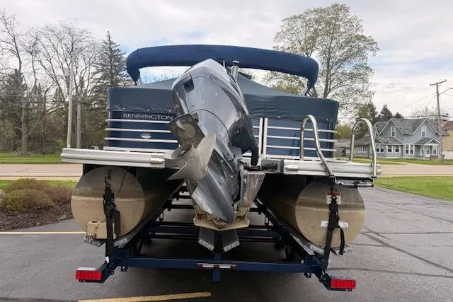 Slide: The Image of 2012 Bennington 2574 GCW pontoon boat on trailer, rear view with motor, parked outdoors. - 28