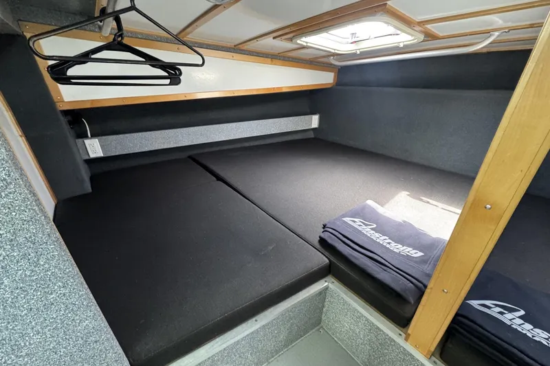 Slide: The Image of 2015 Armstrong Marine Power Cat cabin interior with bed, hangers, and branded towels. - 12
